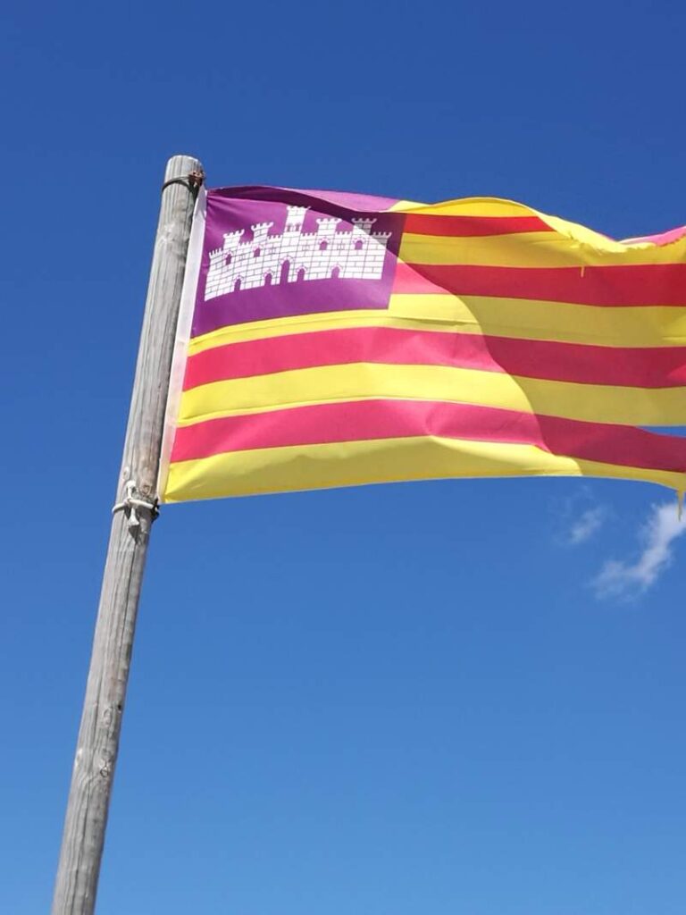 Mallorcan flag flapping in the wind on top of the fortress of Castell de sa Punta Amer in Mallorca, Spain.