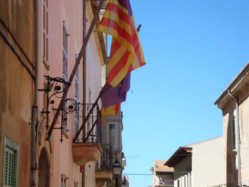 Facade of the Casa de la Vila in Petra village, Mallorca, with flags hanging in front.