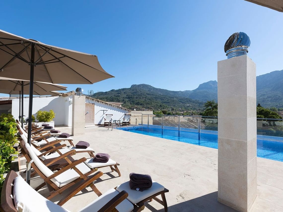 Rooftop swimming pool with panoramic views of the lush Tramuntana mountains at Gran Hotel Sóller, Mallorca.
