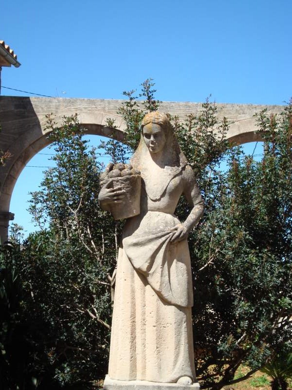 Sculpture of a traditional farm girl, a Pagesa, at the rectory of Petra, Mallorca, Spain.