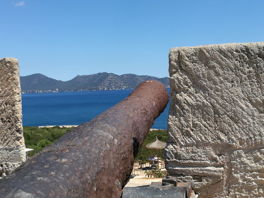 Old original cannon on top of the Punta Amer fortress pointing over the bay of Cala Millor, Mallorca, Spain.