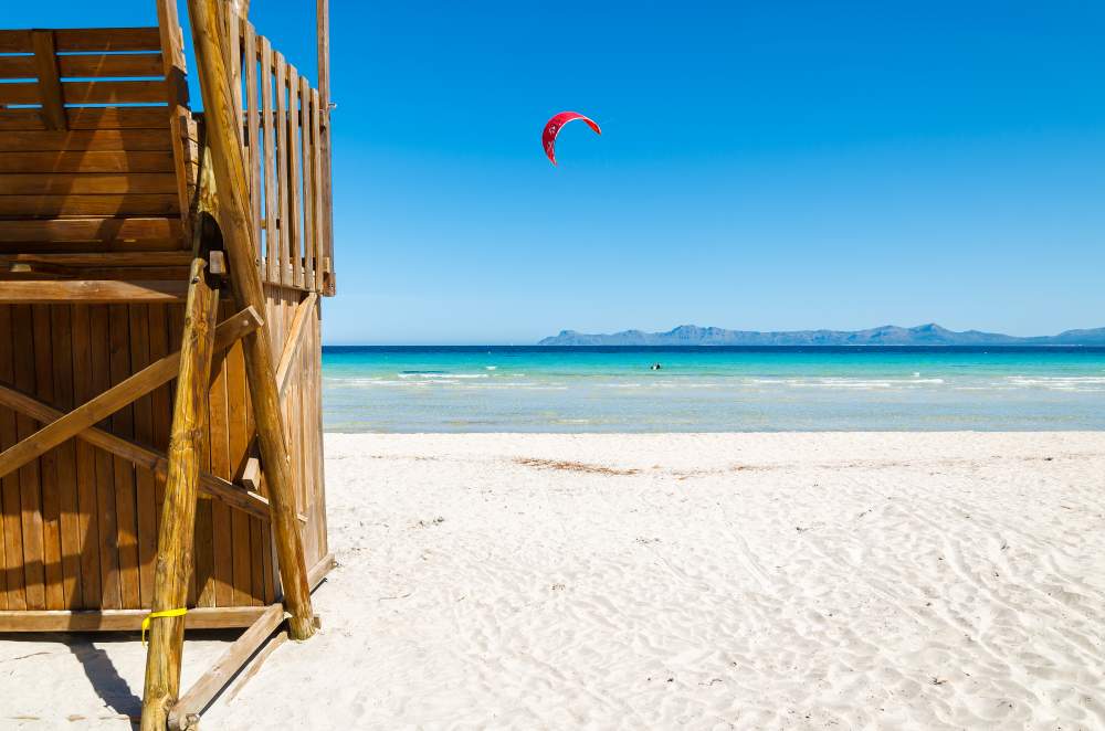 sandy beach with shallow turqoise waters in the summer in Alcudia, Mallorca, Spain.