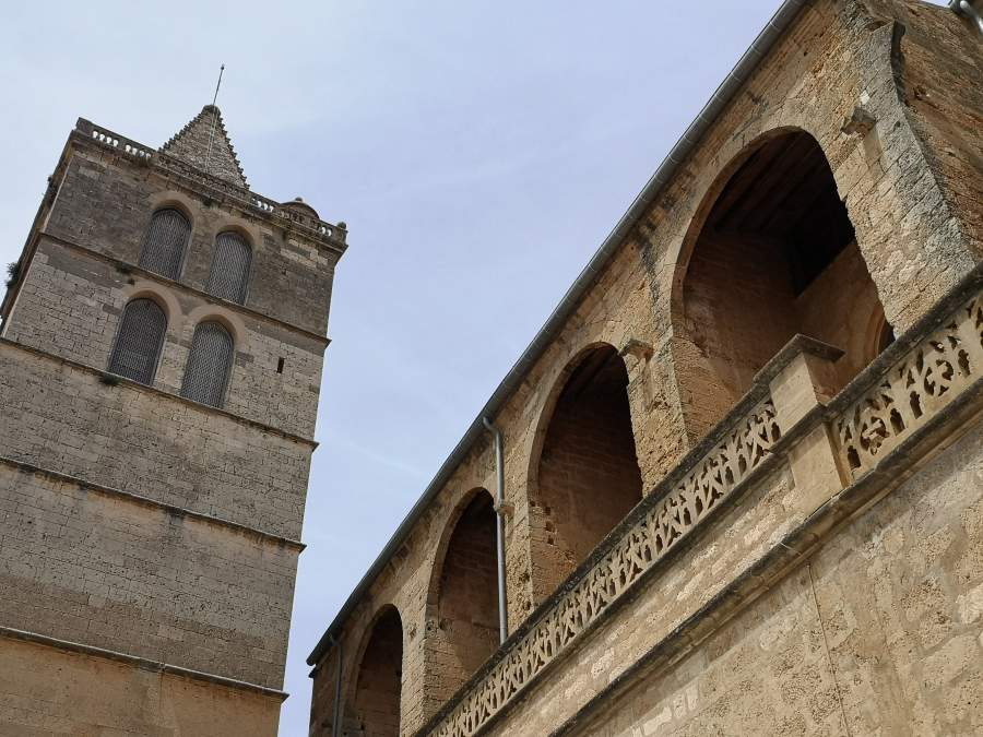 Tower and facade with arches of the Santa Maria church in Sineu town.