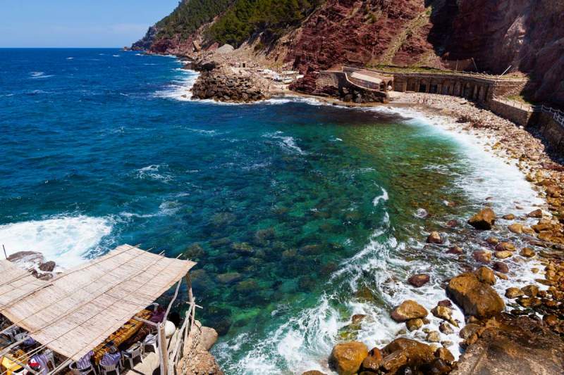 Small natural beach in a rocky cove at the feet of the mountains in Estellencs area, Mallorca, Spain.