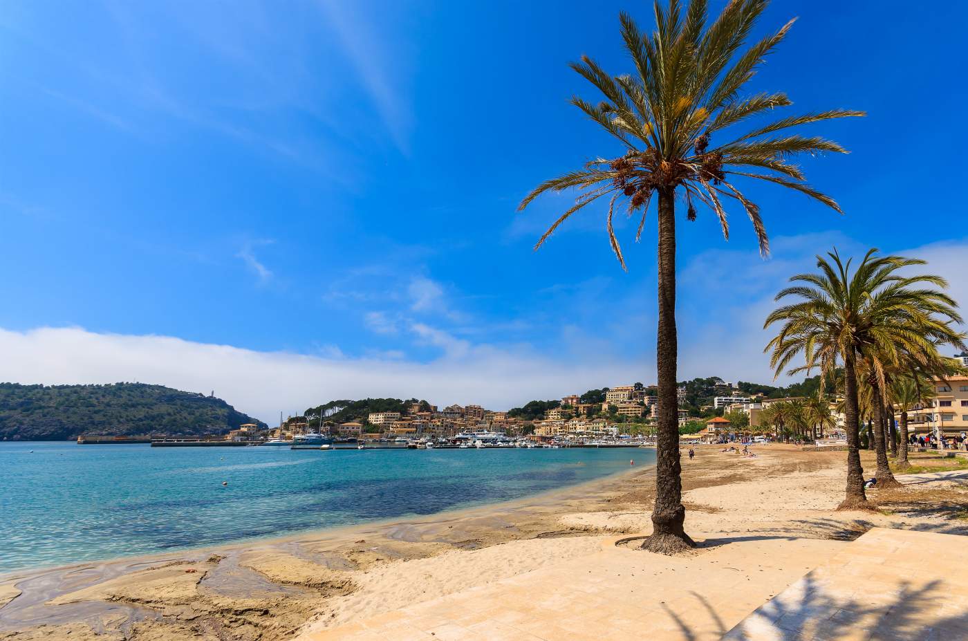 Sandy beach in Port de Sóller, Mallorca, Spain, with mountains in the background.
