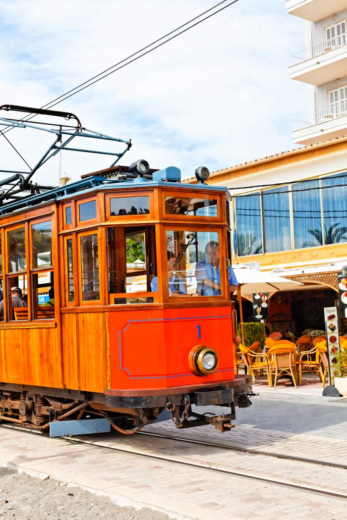 Antique tram driving on the beach promenade of coastal village Port de Sóller, Mallorca, Spain, is a major tourist attraction.