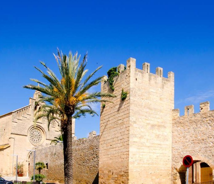 Medieval wall and gate surrounding Alcudia town and church in Mallorca.