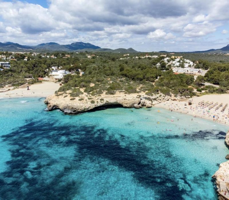 Sunny summer day by the beaches of Cales de Mallorca, Mallorca, with clear shallow waters.