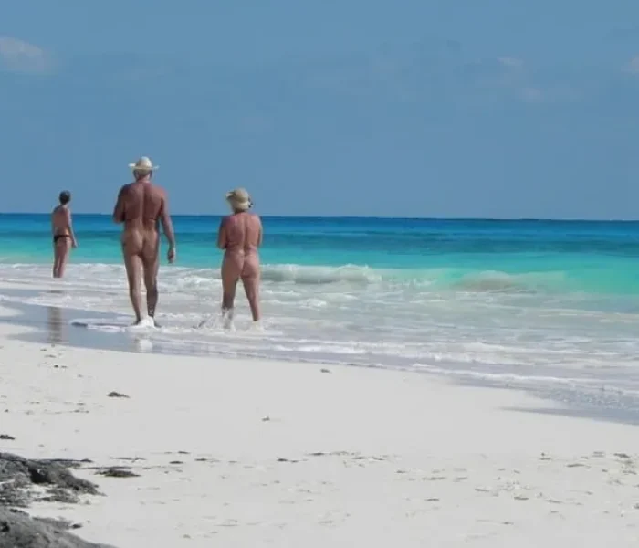 Three nudists walking on a beach in Mallorca, Spain on a sunny summer day.