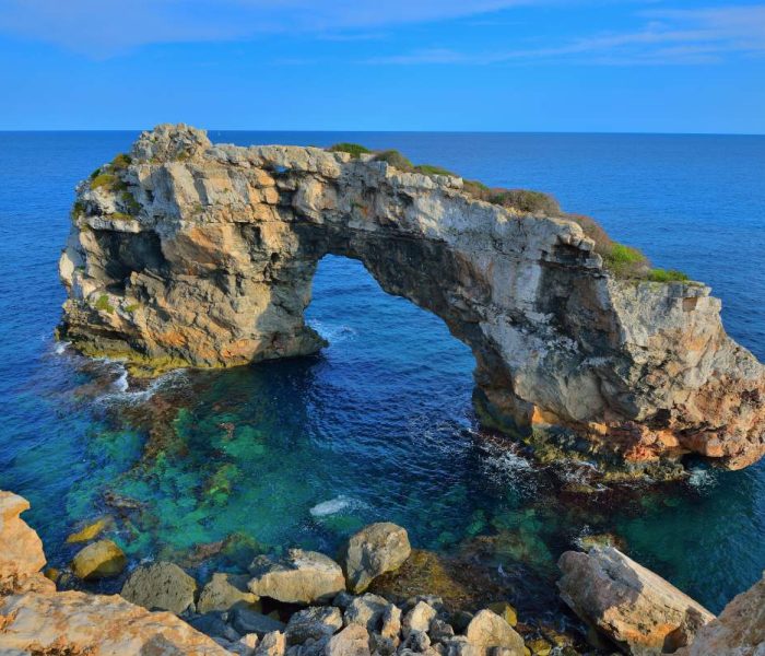Horseshoe shaped rock known as 'Es Pontas' rising from the water in Cala Llombards, Mallorca.