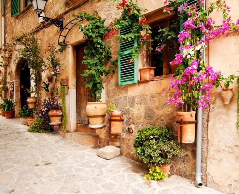 Charming street with house facades decorated with flowers in Valldemossa mountain village, Mallorca island, Spain.